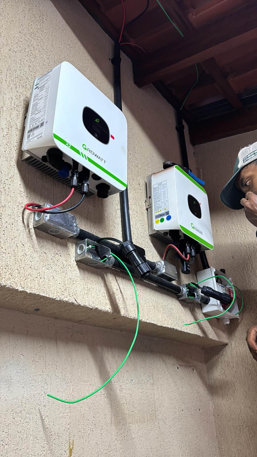 Instalador da VLL Solar finalizando inversores Growatt na parede externa